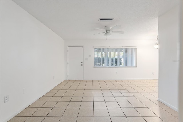 empty room featuring light tile patterned floors, ceiling fan, visible vents, and baseboards