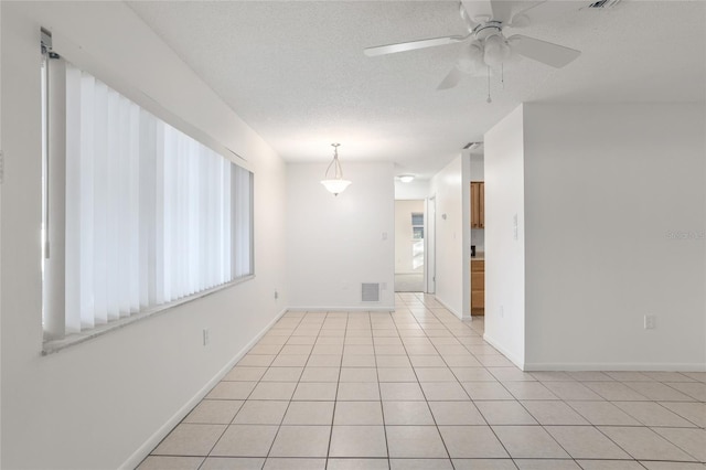 spare room featuring light tile patterned floors, a textured ceiling, baseboards, and a healthy amount of sunlight