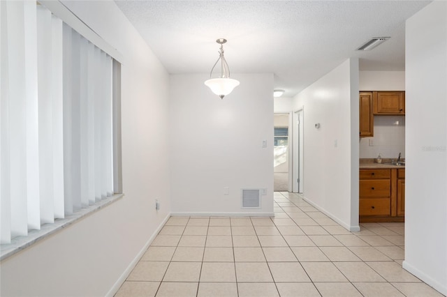 unfurnished dining area with light tile patterned floors, baseboards, visible vents, and a sink