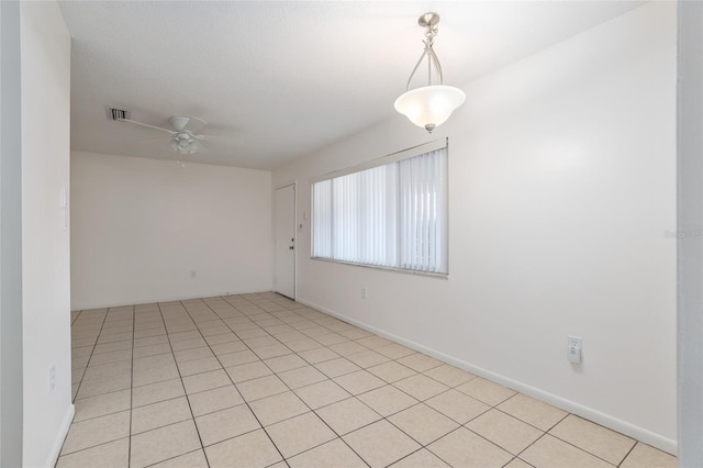 spare room with light tile patterned floors, visible vents, and a ceiling fan