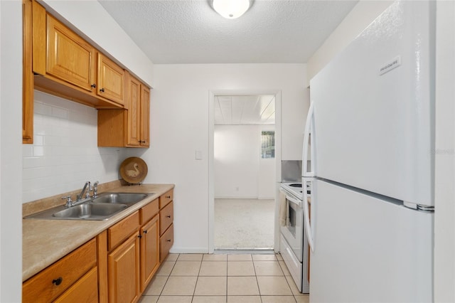 kitchen featuring light tile patterned floors, white appliances, a sink, light countertops, and decorative backsplash