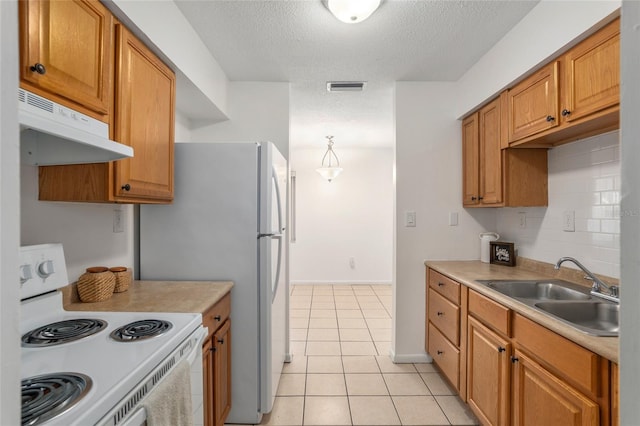 kitchen featuring range hood, light tile patterned floors, visible vents, a sink, and white appliances