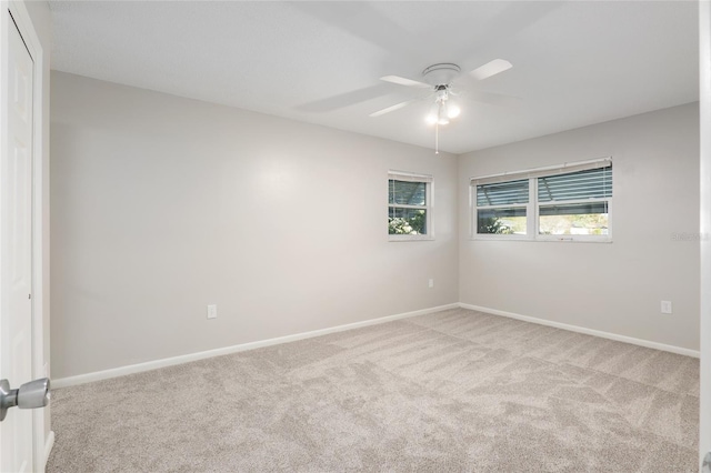 empty room with a ceiling fan, light carpet, and baseboards