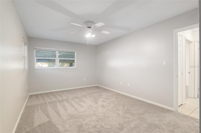 empty room with a ceiling fan, light colored carpet, and baseboards