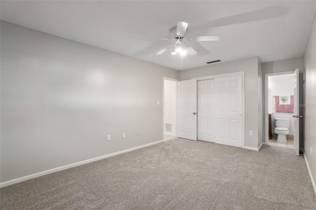 unfurnished bedroom featuring ensuite bathroom, carpet flooring, visible vents, baseboards, and a closet