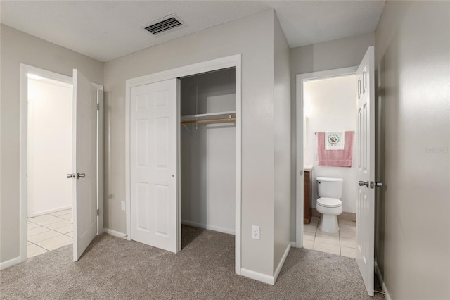 unfurnished bedroom featuring baseboards, visible vents, tile patterned floors, carpet, and a closet