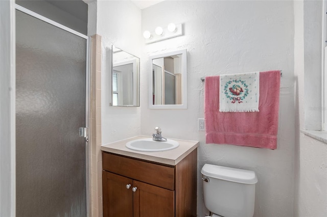 full bathroom featuring a stall shower, vanity, and toilet