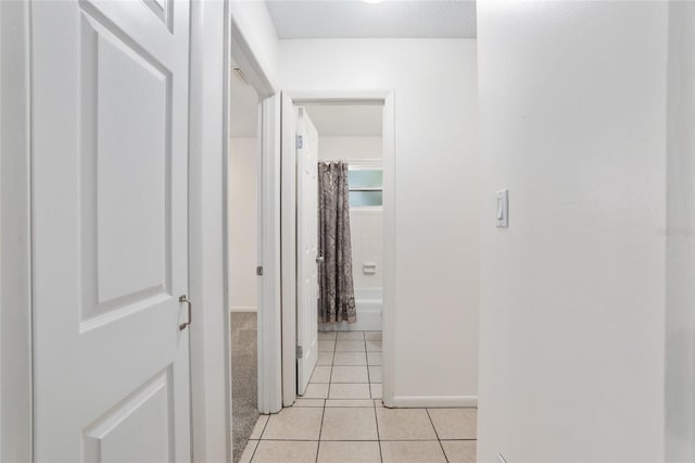 hall with light tile patterned floors and baseboards