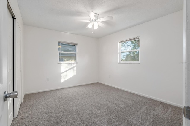 carpeted empty room featuring ceiling fan, a textured ceiling, and baseboards