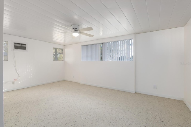 unfurnished room featuring ceiling fan, baseboards, an AC wall unit, and speckled floor