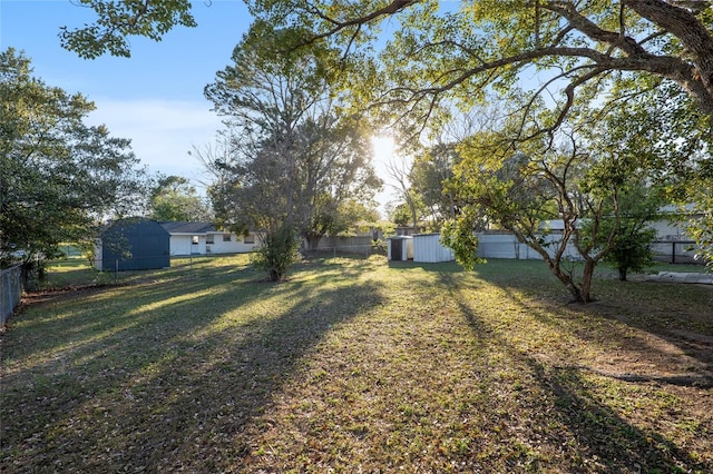 view of yard featuring a fenced backyard, a storage unit, and an outdoor structure