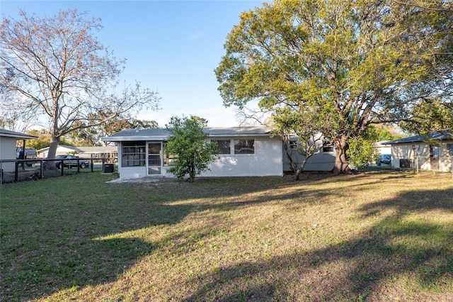 rear view of property featuring a yard, fence, a sunroom, and stucco siding