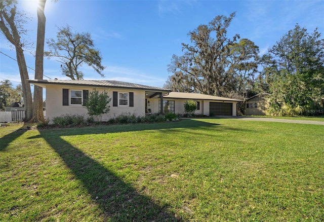 single story home featuring driveway, a front lawn, an attached garage, and stucco siding