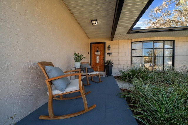 entrance to property featuring covered porch and stucco siding