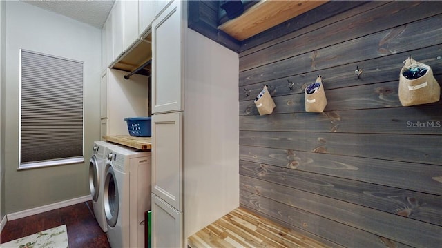 laundry area featuring washing machine and dryer, cabinet space, baseboards, and wood finished floors