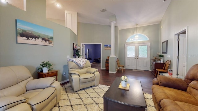 living area featuring light wood finished floors, baseboards, visible vents, french doors, and ornate columns