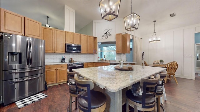 kitchen featuring a center island, lofted ceiling, decorative backsplash, appliances with stainless steel finishes, and a sink