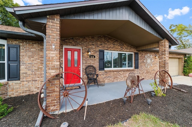 view of exterior entry with an attached garage, concrete driveway, and brick siding