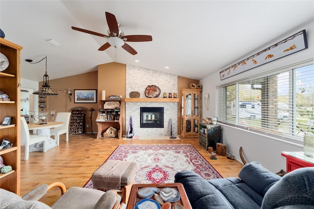 living room featuring lofted ceiling, a fireplace, wood finished floors, and a ceiling fan