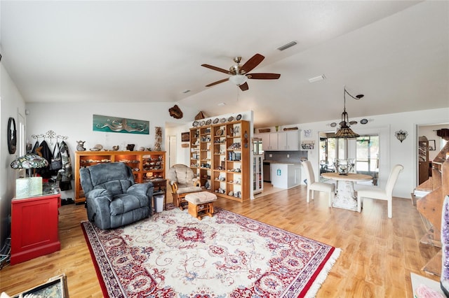 living room with vaulted ceiling, light wood-style flooring, visible vents, and a ceiling fan