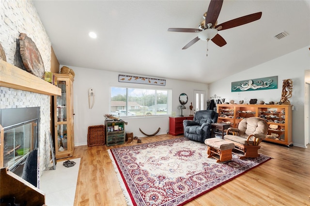 living area featuring visible vents, a ceiling fan, wood finished floors, vaulted ceiling, and a fireplace