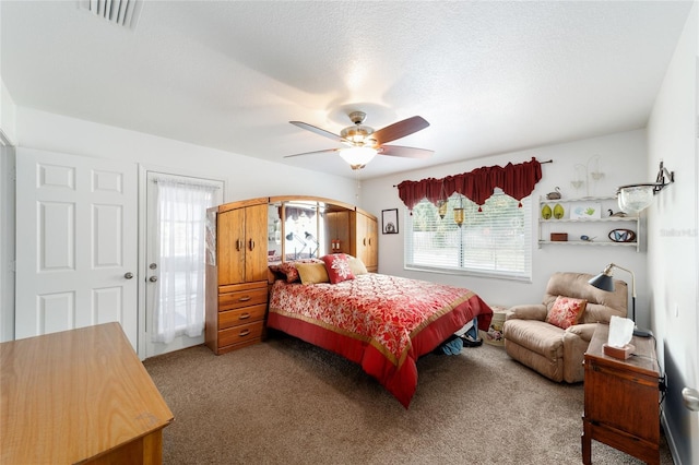 carpeted bedroom with a ceiling fan, multiple windows, visible vents, and a textured ceiling