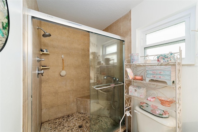 bathroom with toilet, a shower stall, and a textured ceiling