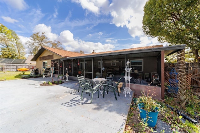 rear view of property featuring a patio area, fence, and a sunroom