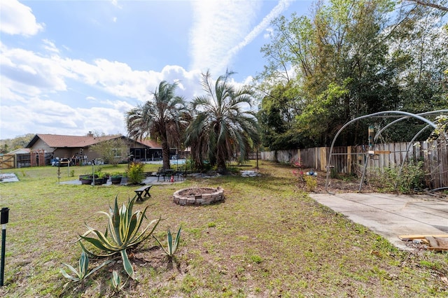 view of yard with a detached carport, fence, and a fire pit