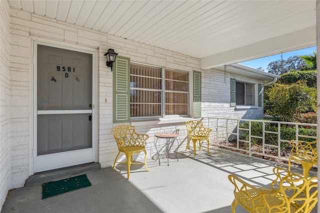 view of exterior entry featuring covered porch and brick siding