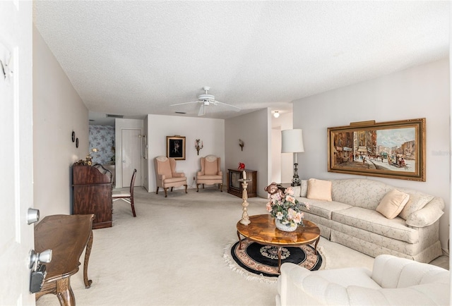 living room featuring a textured ceiling, a ceiling fan, and light colored carpet