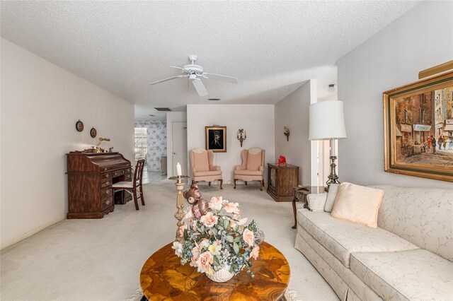 living area with a ceiling fan, light colored carpet, and a textured ceiling