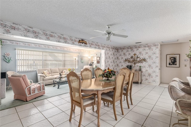 dining room featuring light tile patterned floors, ceiling fan, a textured ceiling, baseboards, and wallpapered walls