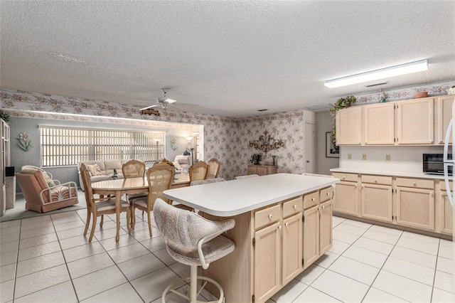 kitchen featuring light countertops, open floor plan, a kitchen island, a textured ceiling, and wallpapered walls