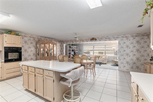 kitchen featuring wallpapered walls, light tile patterned floors, light countertops, and oven