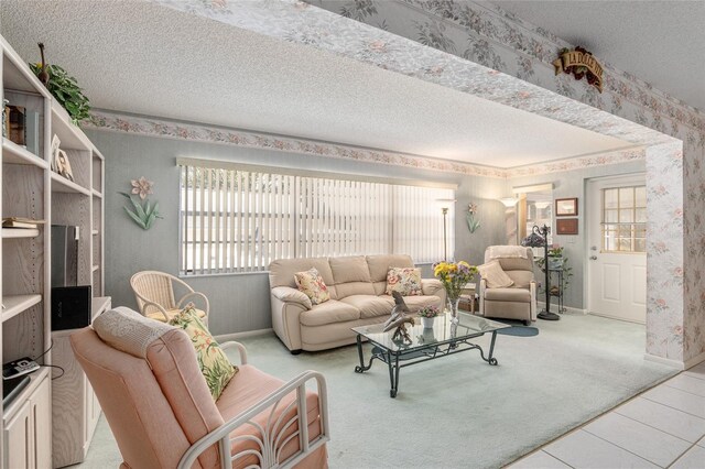 carpeted living area with wallpapered walls, tile patterned flooring, baseboards, and a textured ceiling