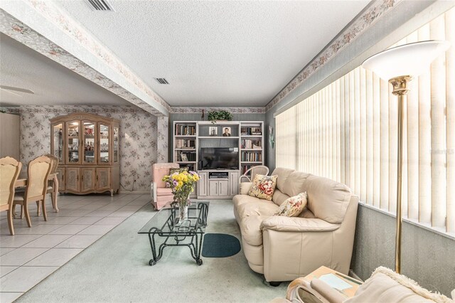 tiled living room with visible vents, a textured ceiling, and wallpapered walls