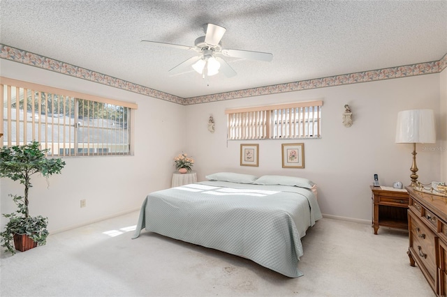 bedroom with light carpet, a ceiling fan, baseboards, and a textured ceiling