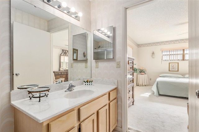 bathroom with wallpapered walls, connected bathroom, a textured ceiling, and vanity