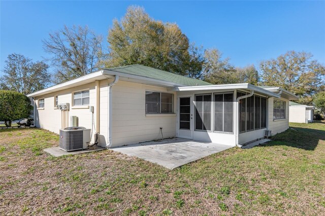 back of property with cooling unit, a sunroom, a lawn, and a patio