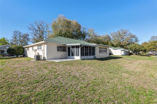 back of property with a sunroom, a patio area, central AC, and a yard