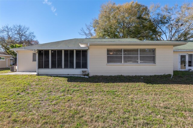 back of property featuring a sunroom, a yard, and central AC unit