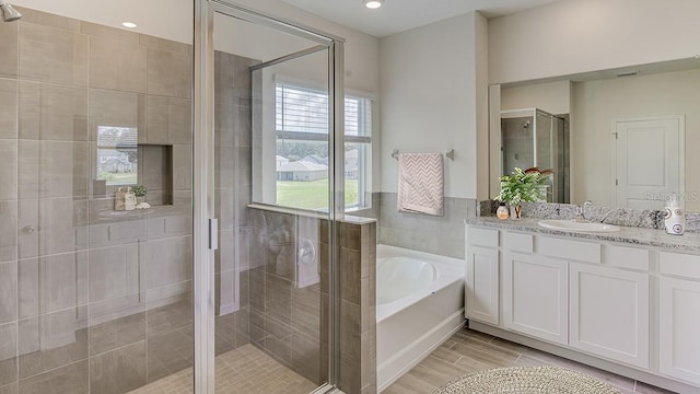 bathroom featuring recessed lighting, wood tiled floor, a shower stall, vanity, and a bath