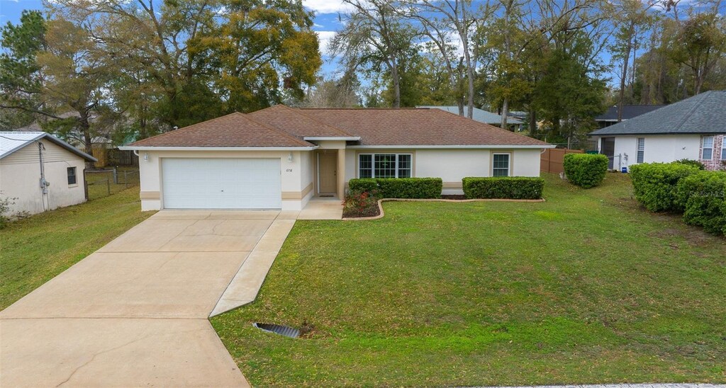 6718 Cherry Rd, Ocala, FL 34472 - single story home with driveway, an attached garage, fence, a front lawn, and stucco siding