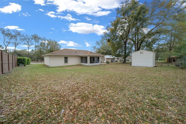 view of yard featuring an outbuilding, a sunroom, fence, and a shed