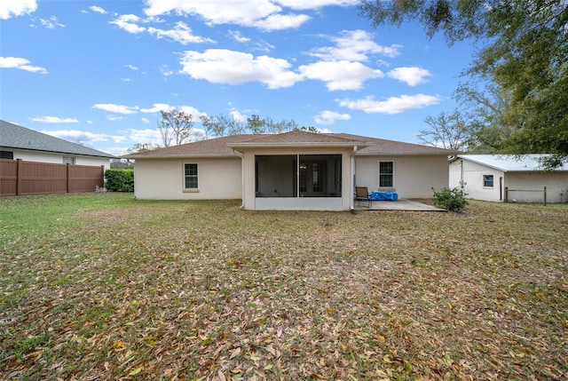 rear view of house with a sunroom, fence, a yard, a patio area, and stucco siding