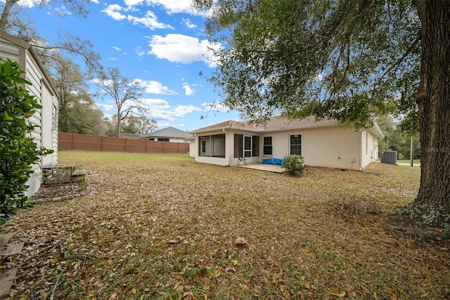 back of property with a yard, a sunroom, fence, and stucco siding