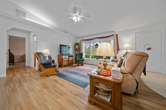 living area featuring lofted ceiling, visible vents, arched walkways, and wood finished floors