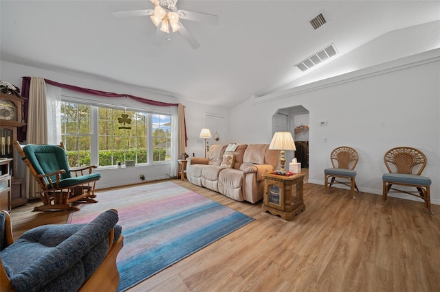 living area with light wood-type flooring, baseboards, visible vents, and vaulted ceiling