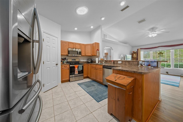 kitchen with light tile patterned floors, visible vents, dark countertops, a peninsula, and stainless steel appliances